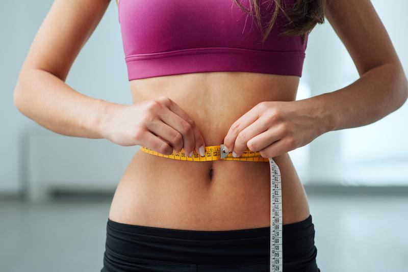 Slim woman measuring her thin waist