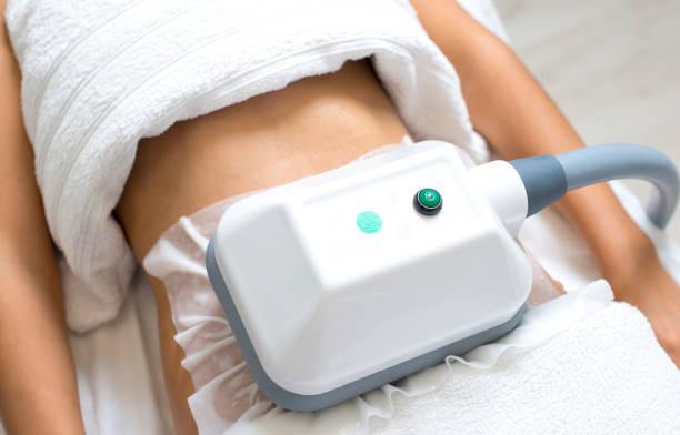 young woman getting cryolipolyse treatment in cosmetic cabinet