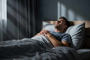 A man lying awake in bed at night staring at the ceiling, unable to sleep during Ozempic treatment.