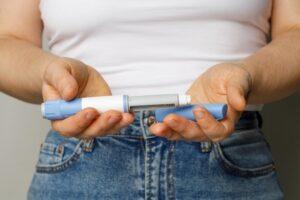 A woman holding semaglutide medication and wondering, “How much does semaglutide cost?”
