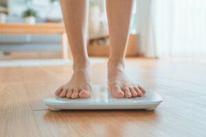 A person stands on a scale and wonders how to get tirzepatide for weight loss.